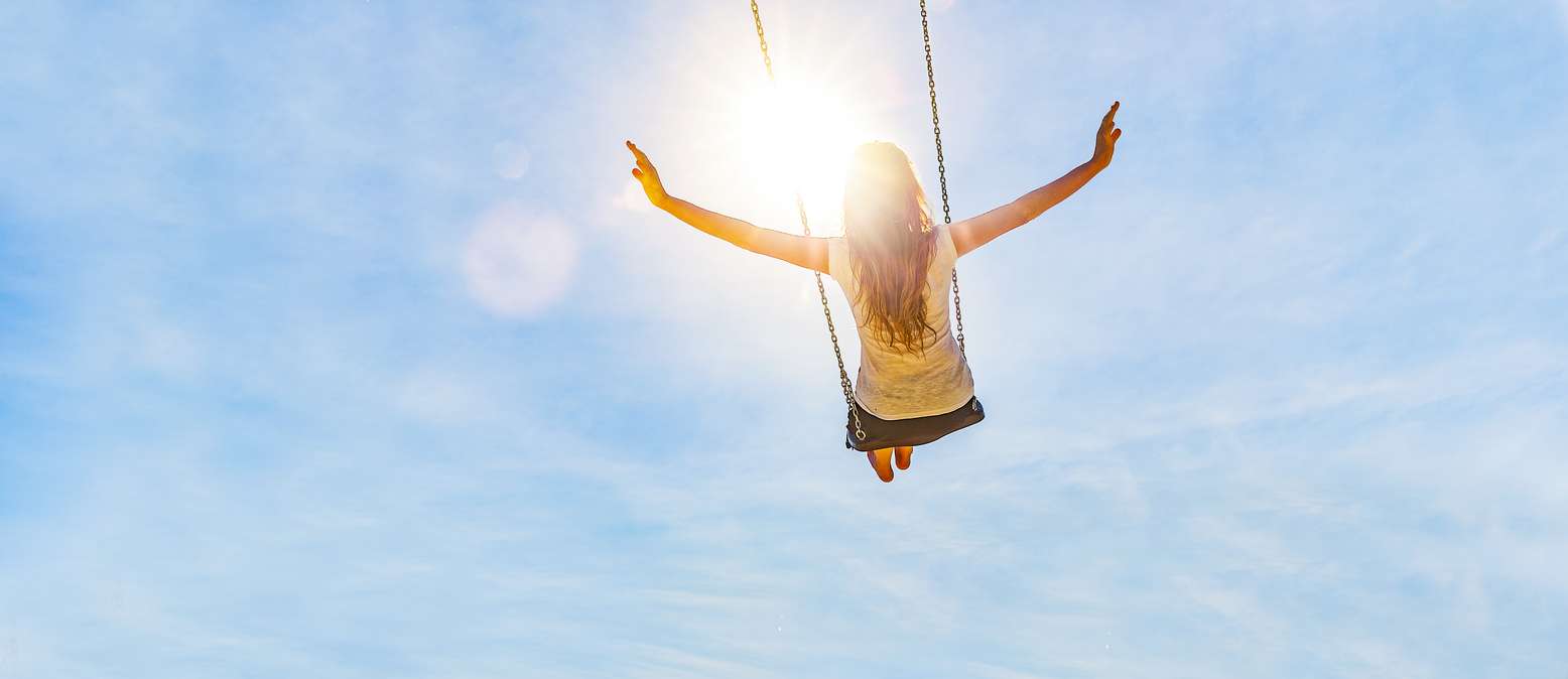Woman on a swing with blue sky in the back light
