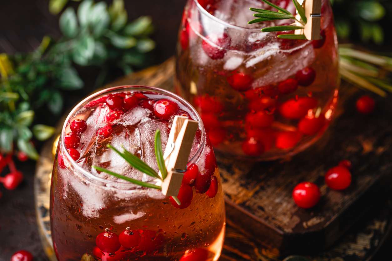 Festive Cranberry and rosemary cocktail with ice on the dark background. Alcoholic or non-alcoholic cocktail.